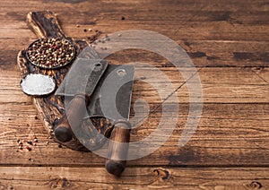 Vintage hatchets for meat on wooden chopping board with salt and pepper on wooden table background