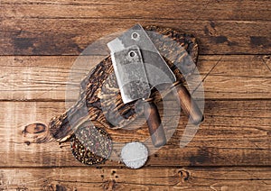 Vintage hatchets for meat on wooden chopping board with salt and pepper on wooden table background