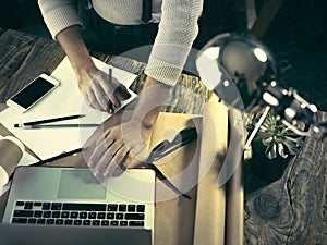 Vintage hipster wooden desktop top view, male hands using a laptop and holding a pencil