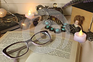 Vintage horizontal still life: printed book, candle glasses, vintage jewelry, small faience doll