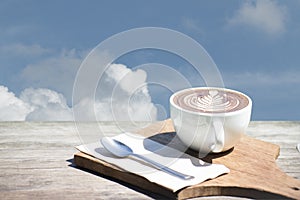 Vintage of hot coffee cup cappuccino art, spoon, tissue, chopping board on wooden table with copy space