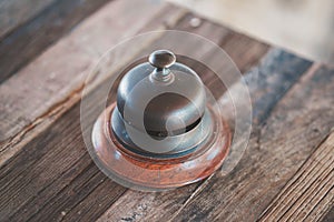 Vintage hotel reception service desk bell on wooden table.