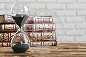 Vintage hourglass against a stack of old books