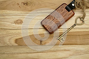 Vintage house key with wooden home keyring on wood board background, property concept, copy space