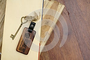 Vintage house key with wooden home keyring on wood board background, property concept, copy space