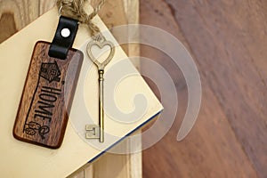 Vintage house key with wooden home keyring on wood board background, property concept, copy space