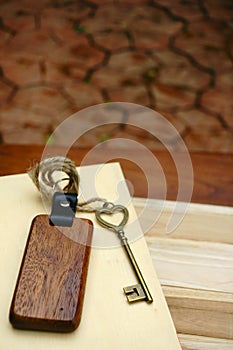 Vintage house key with wooden home keyring on wood board background, property concept, copy space