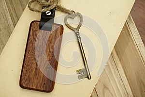 Vintage house key with wooden home keyring on wood board background, property concept, copy space