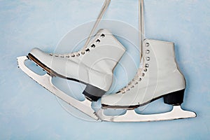 Vintage ice skates for figure skating hanging on the background of blue wall.