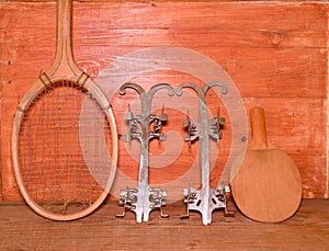 Vintage ice skates, tennis racket and table tennis racket on wooden background. Retro ice skates tennis raket and table tennis rac