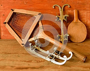 Vintage ice skates and tennis racket on wooden background. Retro ice skates and tennis racket.