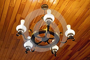 Vintage illuminated chandelier on wooden ceiling in country house