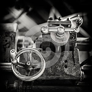 Vintage image of the adjustment knobs of an antique parallel lathe for turning mechanical parts, black and white, tool carriage