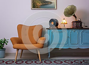 Vintage interior of retro orange armchair, vintage wooden light blue sideboard, old phonograph gramophone and vinyl records