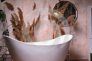 Vintage interior in soft colors with stylish bathtub, mirror and plants.