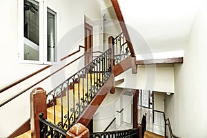 Vintage interior stairs with wooden steps and wooden and black painted metal balustrade in an old dwelling