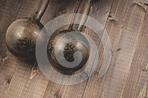 Vintage iron dumbbells on the black wooden floor/Dumbbells in fitness gym on a dark wooden floor. Top view and copy space