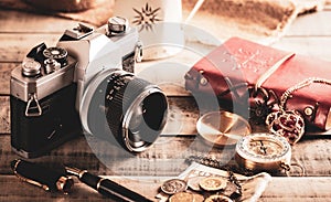Vintage items, pen red book, coins money, compass and retro photo film camera on wood background