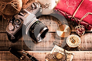 Vintage items, pen red book, coins money, compass and retro photo film camera on wood background