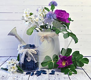 Vintage jar with honey berry and watering can with wild flowers