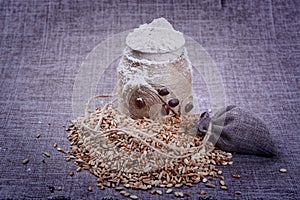 Vintage jar of white flour stands in the middle of a pile of grain o