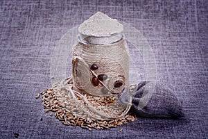 Vintage jar of white flour stands in the middle of a pile of grain o