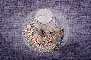 Vintage jar of white flour stands in the middle of a pile of grain o