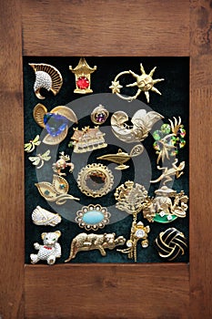 Vintage jewelry, a variety of brooches in a wooden frame