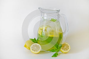 Vintage jug with refreshing non alcoholic mojito drink with lemon slices, mint leaves and ice. Studio shot of iced lemonade