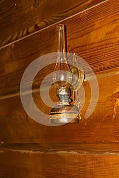 Vintage kerosene lamp with glass and wick hanging on a wooden wall