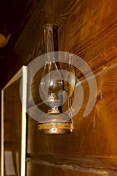 Vintage kerosene lamp with glass and wick hanging on a wooden wall