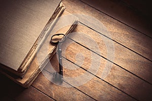 Vintage key and old books on wooden table.