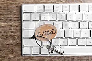 Vintage key with tag and keyboard on wooden table, top view. Keyword concept