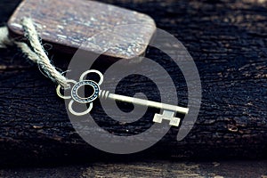 Vintage key with wooden home keyring hanging on old wood plank with blur green garden background