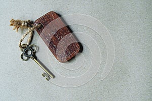 Vintage key with wooden home keyring hanging on old wood plank with blur green garden background, copy space