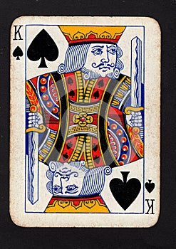 A vintage king of spades playing card on a black background.