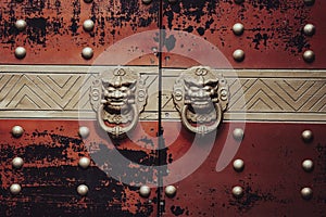 Vintage knocker door handles Asian style on the red painted doors. Lion door handle rings