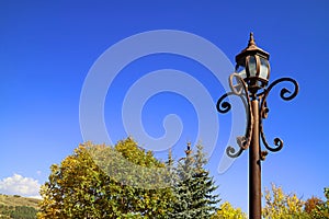 Vintage Lamppost against Fall Foliage and Vivid Blue Clear Sky