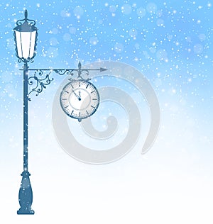 Vintage lamppost with clock in snowfall on blue