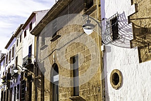 Vintage lantern and beautiful twisted wrought-iron grill on the window on the facade of an old house. Architectural detail