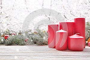 Vintage lantern red candles with Christmas fir tree garland on wooden board on window sill over nature snowing tree park