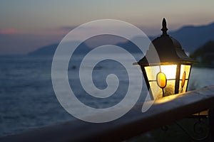 Vintage lantern shines at sunset in the background of the sea