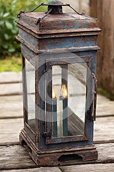 Vintage lantern on a wooden terrace in a garden.