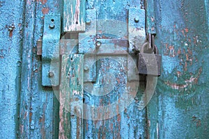 Vintage latch and closed padlock on weathered scratched wooden door. Concept of security and privacy protection. Textured grunge