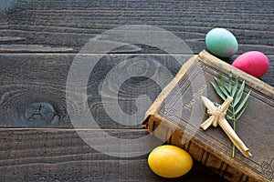 Vintage Leather Bible with grass cross, palm leaves, Colorful Easter Eggs on Dark Rustic Wood Board