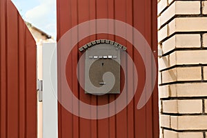 Vintage letter box on red fence near brick wall outdoors