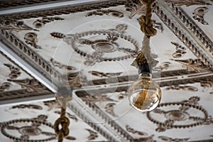 The vintage light bulb hanging on the ceiling of an old building. A Retro Edison light bulb hanging on the ceiling