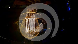 Vintage lightbulb on dark background with bright yellow shining wire.Close up of industrial lamp light.Illumination