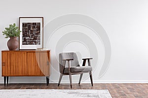 Vintage living room interior with retro furniture and poster, real photo with copy space on the white wall