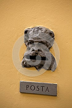 Vintage mailbox gap on old building wall. Slot with inscription POSTA or Mail on metal plate and bizarre head of